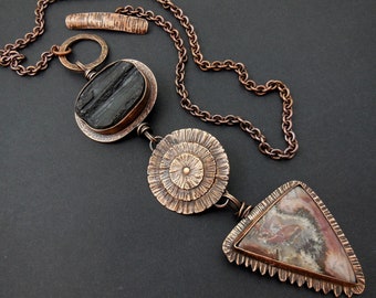 May include: A copper necklace with a black and brown agate stone pendant, a copper circle pendant with a textured design, and a copper triangle pendant with a brown and white agate stone.