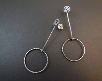 May include: A pair of silver earrings with a spiral design at the top and a circular hoop at the bottom.