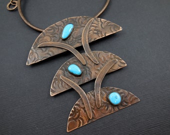 May include: A copper necklace with three crescent-shaped pendants, each with a textured surface and a turquoise stone.