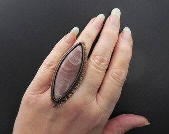 May include: A copper ring with a pink and white oval shaped stone set in a decorative copper frame.