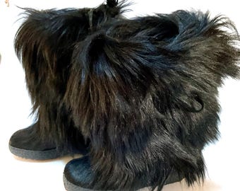 May include: A pair of black faux fur boots. The boots have a round toe and a thick, textured sole. The upper part of the boots is covered in long, shaggy black faux fur.