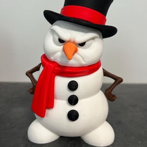 May include: A white snowman figurine with a grumpy facial expression, wearing a black top hat with a red band and a red scarf. The snowman has a bright orange carrot nose, three black circular buttons on its torso, and brown stick-like arms.