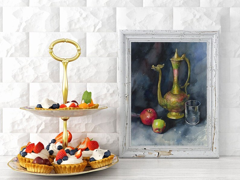 May include: A two-tiered gold serving stand with a white and gold floral pattern. The stand is filled with small pastries topped with whipped cream, blueberries, and strawberries. A framed watercolor painting of a still life with a green and gold pitcher, apples, and a glass sits on a white tiled surface behind the stand.