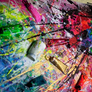 May include: A close-up of a colorful abstract painting with splatters of paint and tubes of paint on a canvas. The painting is in shades of red, pink, green, blue, yellow, and black. The text "Anna Marija Bulka" is visible in the upper right corner of the image.