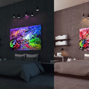 May include: A bedroom with a bed, a desk, and a large abstract painting on the wall. The painting is colorful and has a lot of different colors, including red, yellow, blue, green, and purple. The painting is lit up by a UV light, which makes the colors glow. The room is dark, and the only light is coming from the UV light and the lamps on the ceiling.
