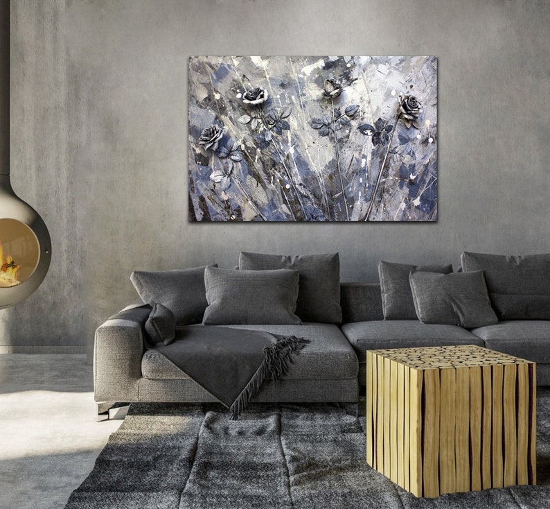 May include: A contemporary living room with a grey sofa, rug, and a wooden coffee table. Above the sofa hangs a large abstract painting of grey and blue roses. A fireplace provides a warm ambiance to the room.
