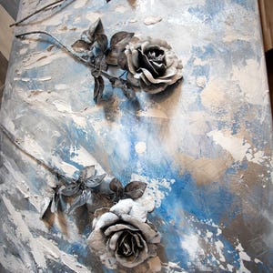 May include: Abstract artwork with textured grey and white roses set against a blue and grey backdrop. The roses are 3D, with detailed petals and leaves. The piece has a modern, artistic aesthetic, suitable for home decor.