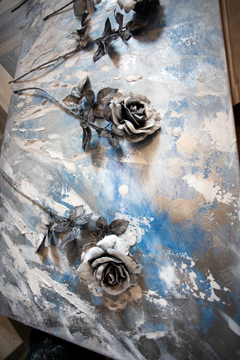 May include: Abstract artwork with textured grey and white roses set against a blue and grey backdrop. The roses are 3D, with detailed petals and leaves. The piece has a modern, artistic aesthetic, suitable for home decor.