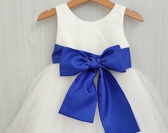 Può includere: Abito in tulle bianco con un nastro e un fiocco in raso blu reale.