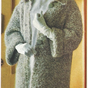 Könnte beinhalten: Ein Vintage-Mantel in knielanger Länge aus einem strukturierten, hellgrauen Stoff. Der Mantel hat breite Revers, drei Knöpfe und weite Ärmel. Die Person im Bild trägt weiße Handschuhe und ein weißes Oberteil. Ein klassisches Kleidungsstück.