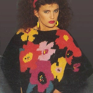 May include: A black sweater with a colourful floral pattern. The sweater has a wide neckline and a loose fit.