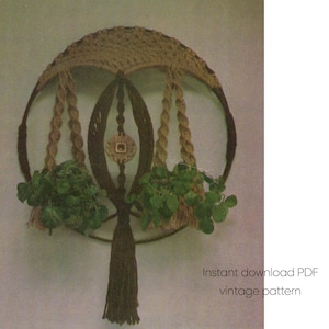 May include: A vintage macrame plant hanger with a circular design. The plant holder is made of brown and tan rope, with two hanging baskets holding green plants. The design includes a decorative tassel and the text "Instant download PDF vintage pattern."