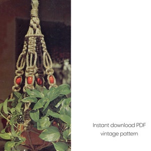 May include: A macrame plant hanger made of natural-colored rope, holding a potted plant with green leaves. The hanger features decorative knots and red beads. Text on the right says "Instant download PDF vintage pattern".