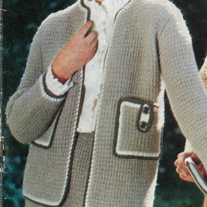 May include: A woman wearing a light gray knit skirt suit with a white blouse. The suit has a textured pattern with dark trim and pocket details. The woman is smiling and wearing a white hat.