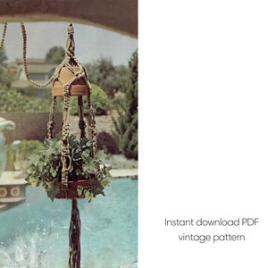 Könnte beinhalten: Ein Vintage-Makramee-Pflanzenaufhänger mit einem Holztopf, der mit grünen Blättern gefüllt ist. Das beige Seildesign hat Holzperlen und eine lange Quaste. Der Hintergrund zeigt einen Pool und Grün. Der Text lautet "Sofort-Download PDF Vintage-Muster."