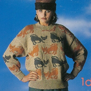 May include: A beige knit sweater with orange and black animal patterns. The sweater has long sleeves and a ribbed hem and cuffs. The person is wearing a brown hat with a black band and gold hoop earrings. The background is a gradient of blue.