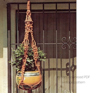 Puede incluir: Un colgador de plantas de macramé vintage con una maceta de cerámica amarilla y verde llena de vegetación. El colgador de plantas está hecho de cuerda marrón y presenta cuentas de madera. La imagen incluye el texto "Instant download PDF vintage pattern".