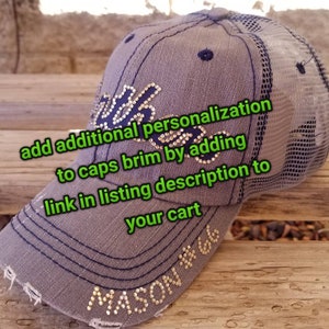 Puede incluir: Una gorra de b&eacute;isbol gris y negra con una parte trasera de malla. La gorra tiene una visera azul marino y est&aacute; decorada con diamantes de imitaci&oacute;n dorados. El texto "MASON #66" est&aacute; escrito en diamantes de imitaci&oacute;n en la parte delantera de la gorra. El texto "add additional personalization to caps brim by adding link in listing description to your cart" est&aacute; escrito en texto verde en la imagen.
