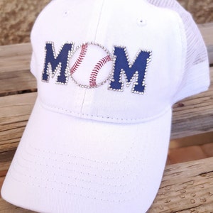 May include: White baseball cap with a blue and white rhinestone MOM design and a baseball graphic.
