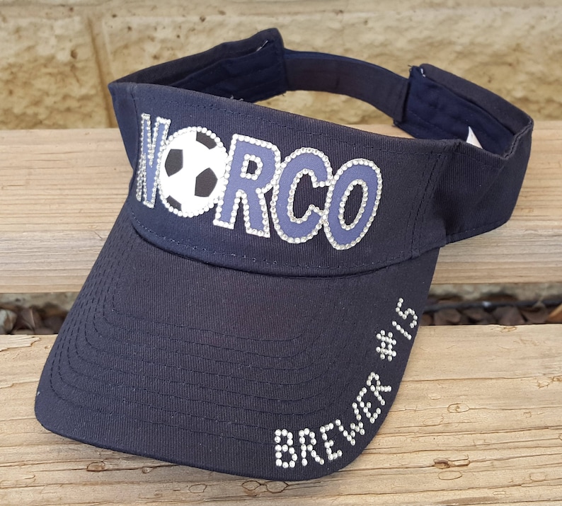 May include: A black visor with a white soccer ball and the word "WORCO" in rhinestones. The visor also has the text "Brewer #15" in rhinestones.