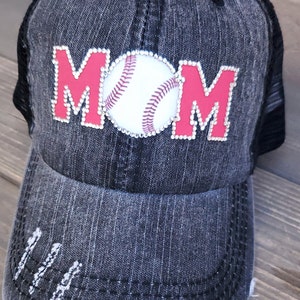 May include: A black and gray distressed denim baseball cap with a red and white baseball and the word "MOM" in rhinestones.