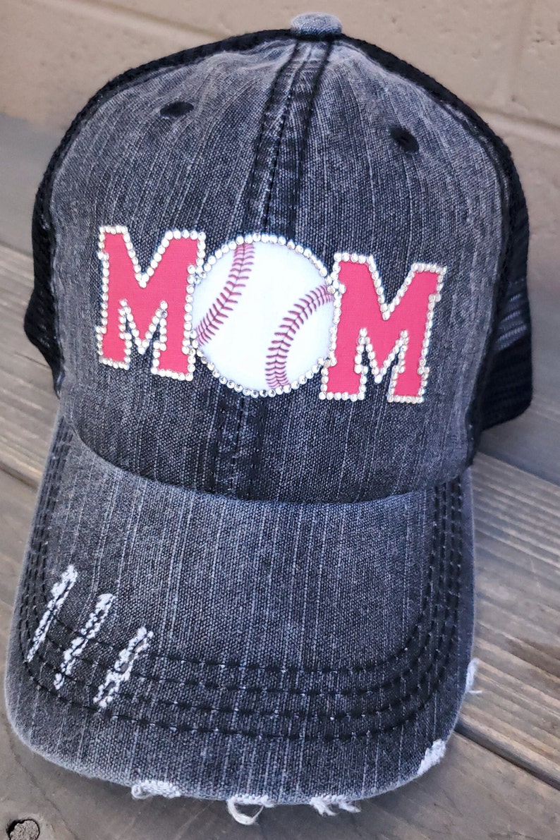 May include: A black and gray distressed denim baseball cap with a red and white baseball and the word "MOM" in rhinestones.