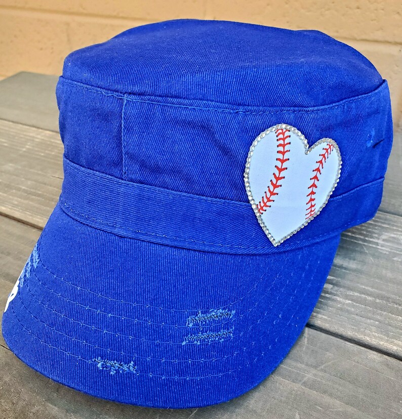 Pode incluir: Bon&eacute; azul royal de estilo militar com aba desgastada. Um patch branco em forma de cora&ccedil;&atilde;o, adornado com strass, apresenta um design de beisebol com costuras vermelhas. O bon&eacute; tem uma coroa estruturada e uma pequena viseira.