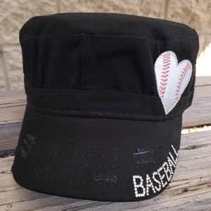 Pode incluir: Bon&eacute; de beisebol preto em estilo militar com aba desgastada. Um patch de beisebol branco em forma de cora&ccedil;&atilde;o est&aacute; na lateral. A palavra "BASEBALL" &eacute; escrita com strass brancos na aba.