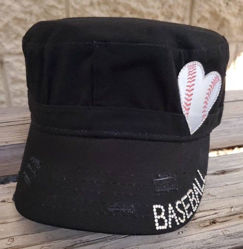 Pode incluir: Bon&eacute; de beisebol preto em estilo militar com aba desgastada. Um patch de beisebol branco em forma de cora&ccedil;&atilde;o est&aacute; na lateral. A palavra "BASEBALL" &eacute; escrita com strass brancos na aba.