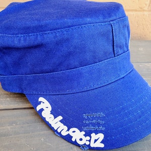 Pode incluir: Bon&eacute; azul royal de estilo militar com aba reta e coroa estruturada. O texto "Psalm 96:12" est&aacute; impresso em branco na aba. O bon&eacute; tem um visual desgastado.