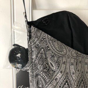 May include: A black and silver paisley patterned dress with a black lining and a zip closure. The dress has a label that says "Christine".