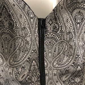 May include: A black and silver strapless dress with a paisley pattern and a black zip at the back.