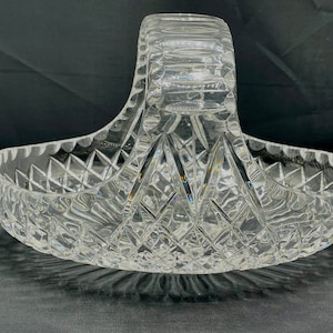 May include: A clear glass serving bowl with a cut glass design and a handle. The bowl is oval shaped and has a diamond pattern.