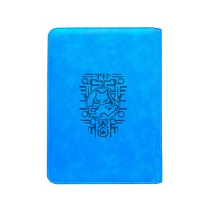 May include: A bright blue rectangular notebook with rounded corners. The front cover features a centered black graphic design depicting a stylized cat-like creature enclosed within a circular frame, surrounded by intricate geometric line patterns.