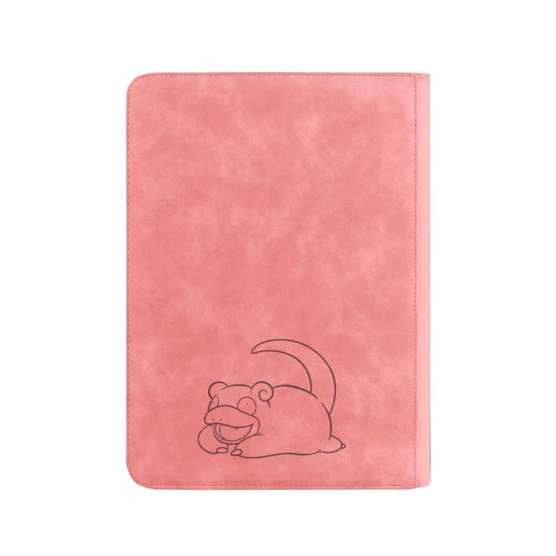 Pu&ograve; includere: Un taccuino o portfolio rettangolare rosa con una superficie strutturata. Un disegno a contorno nero di un personaggio dei cartoni animati &egrave; sul davanti. Il taccuino ha un bordo cucito e un retro rosa pieno.