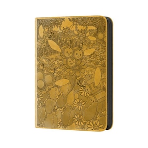 May include: A golden-yellow zippered binder with a detailed engraved design. The design features cartoon bees, flowers, and honeycomb patterns. The binder has a black spine and appears to be made of leather or a similar material.