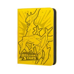 May include: Yellow card binder featuring a black and yellow graphic of a creature and the text "Sword & Shield Brilliant Stars". The binder has a black zipper and is designed to hold trading cards.