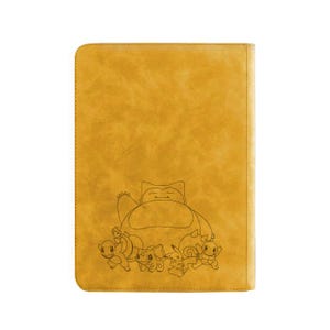May include: Mustard-colored, rectangular notebook or portfolio featuring a detailed line drawing of Snorlax and other Pok&eacute;mon characters. The cover has a textured, leather-like appearance and a stitched border.