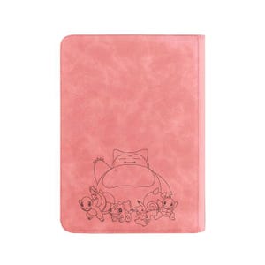 May include: Pink faux leather binder featuring a black line drawing of a Snorlax and other Pok&eacute;mon characters. The binder has a textured surface and a stitched border.