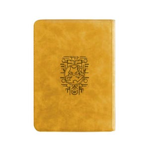 May include: A rectangular mustard yellow notebook with rounded corners. The front cover features a centered dark brown embossed graphic of a stylized cat-like creature surrounded by geometric patterns and abstract symbols.