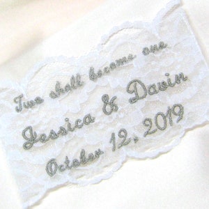 May include: White lace garter with silver glitter embroidery. The text reads "Two shall become one Jessica & Dawin October 12, 2019".