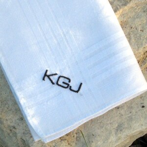 May include: White linen handkerchief with black embroidered initials "K.G.J."