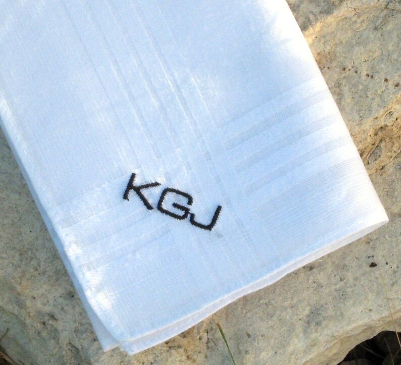May include: White linen handkerchief with black embroidered initials "K.G.J."