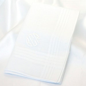 May include: White linen pocket square with a white embroidered monogram in the center. The pocket square has a white border with a subtle pattern.