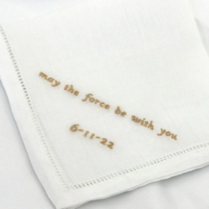 May include: White linen handkerchief with gold embroidery that reads "may the force be with you" and the date "6-11-22".