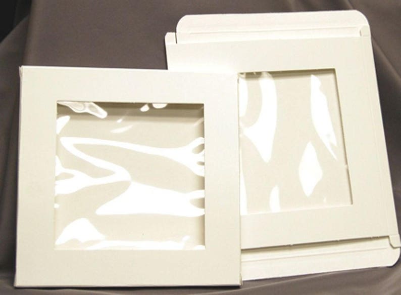 May include: Two white cardboard boxes with clear plastic windows. The boxes are designed to display and protect items.