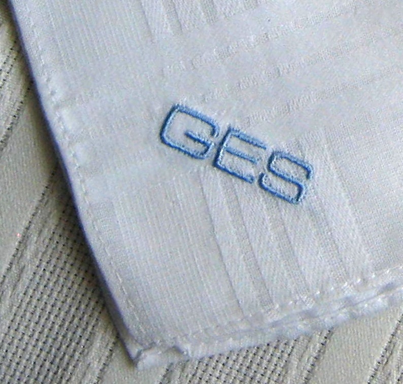 May include: White handkerchief with blue embroidered lettering that reads "GES".