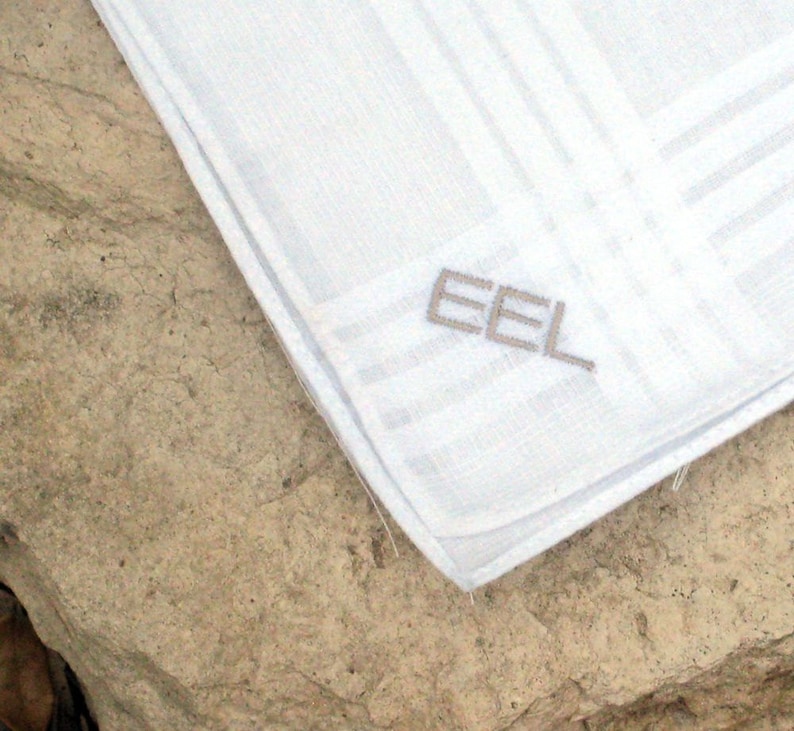 May include: White linen handkerchief with a gray embroidered "EEL" logo.