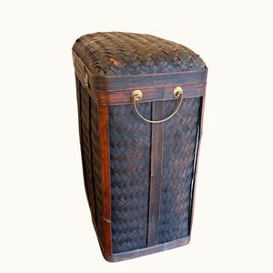 May include: A rectangular, dark brown woven bamboo storage basket with a hinged lid. The basket features brass handles and trim. The woven pattern creates a textured surface. The basket is designed for storage.