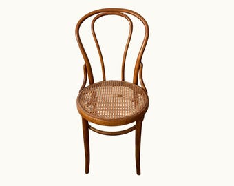 Silla de café antigua estilo Thonet de madera curvada con asiento de mimbre.